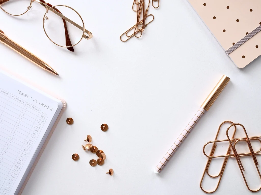 A checklist and notebook on a desk next to a laptop